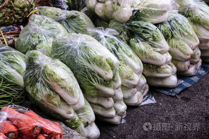 许多塑料袋中的蔬菜都放在地板上在户外市场上销售